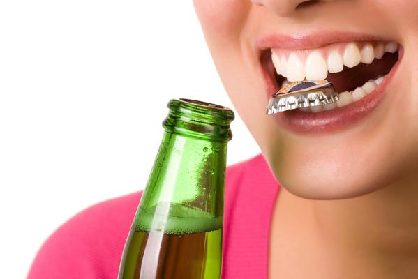 person holding bottle cap in teeth