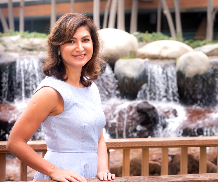 Torrance dentist Doctor Sanaz Hamzehpour smiling in front of a small waterfall