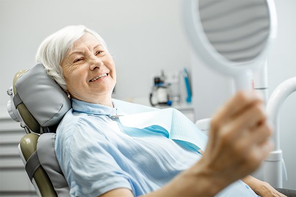 Woman in dental chair looking at her smile