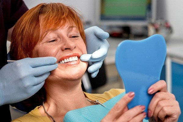 Woman in dental chair looking at smile in mirror