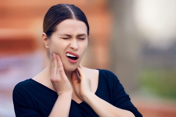 woman with toothache holding jaw