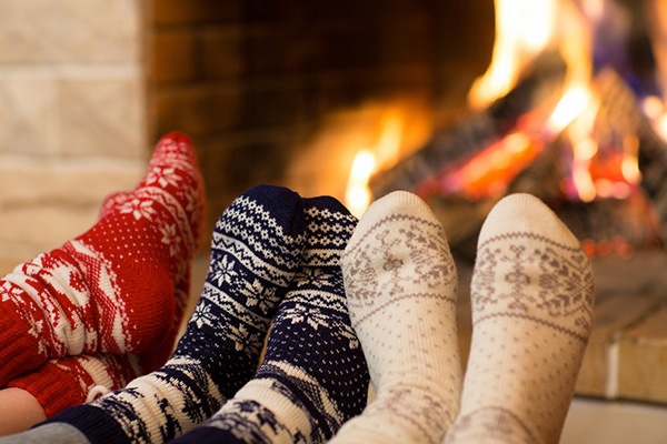 Three pairs of feet in socks by the fireside