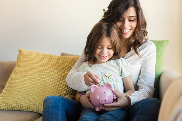 Mother and daughter filling a piggy bank