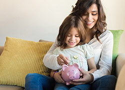 Mother and daughter putting coins in piggy bank