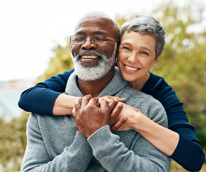 Senior couple hugging and smiling after restorative dentistry in Torrance