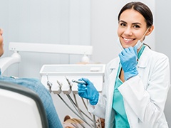 Dentist smiling while holding face mask with glove