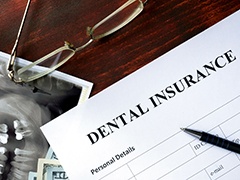 Dental insurance paperwork on desk with X-rays and glasses