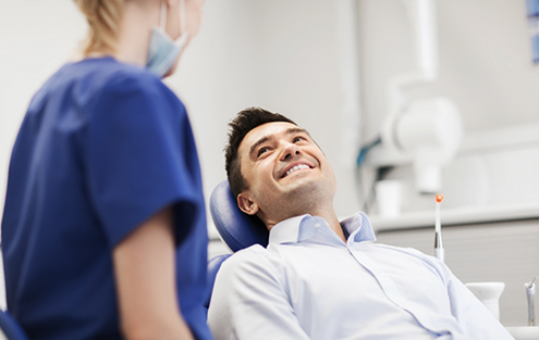 Man in dental chair smiling at his dentist