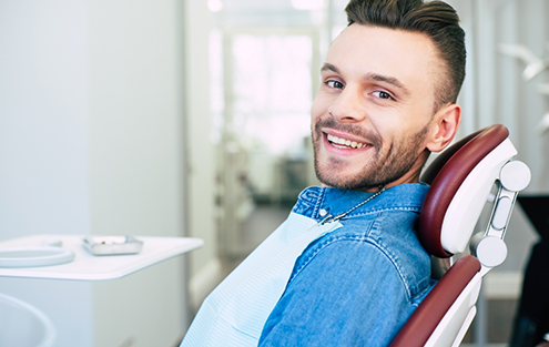 Man in denim jacket smiling in dental chair