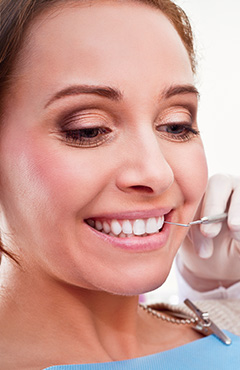 Woman receiving dental exam after dental implant tooth replacement