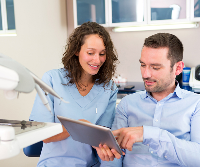 Dentist showing a tablet to a patient before sinus lifts in Torrance