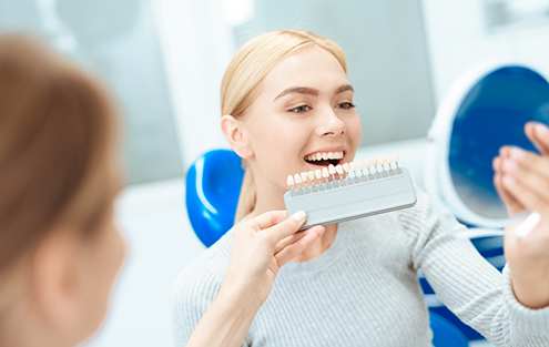 Dentist holding a shade guide in front of a smiling patient