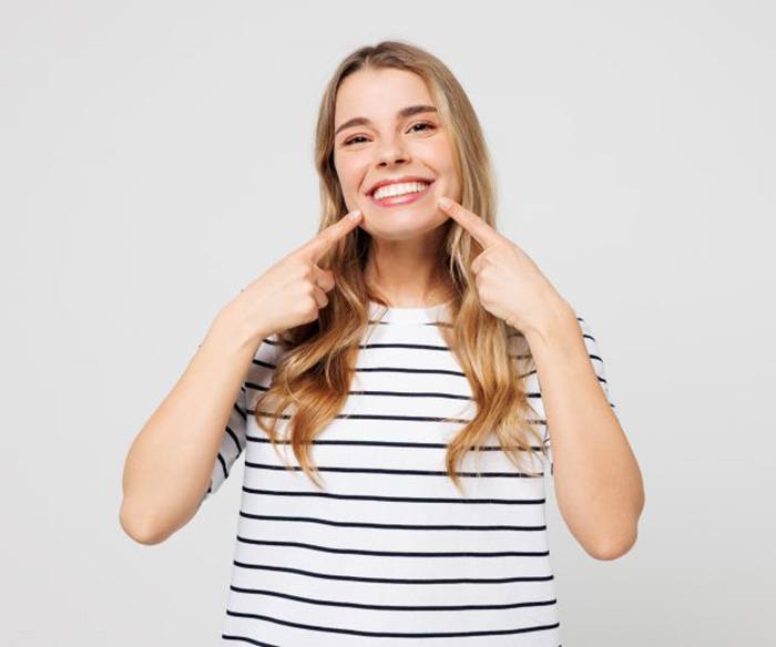Happy young woman pointing at her smile