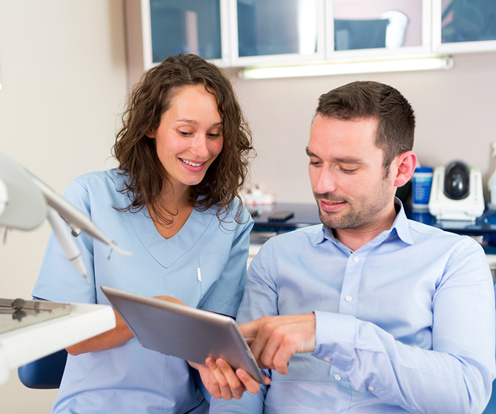 Dental team member showing a tablet to a patient with tooth colored fillings