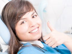 A young girl giving the thumbs up in the dentist chair