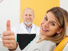 A smiling woman at the dentist’s office showing a thumb’s up 