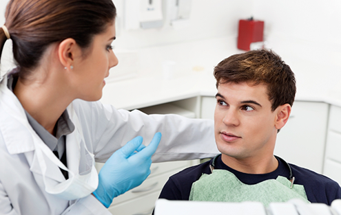 Young man in dental chair talking to dentist
