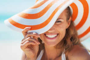 woman smiling behind a floppy hat