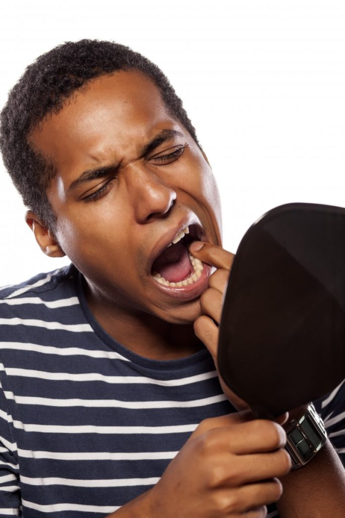 man looking in mirror at teeth