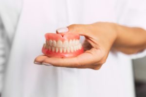 doctor holding dentures in Torrance