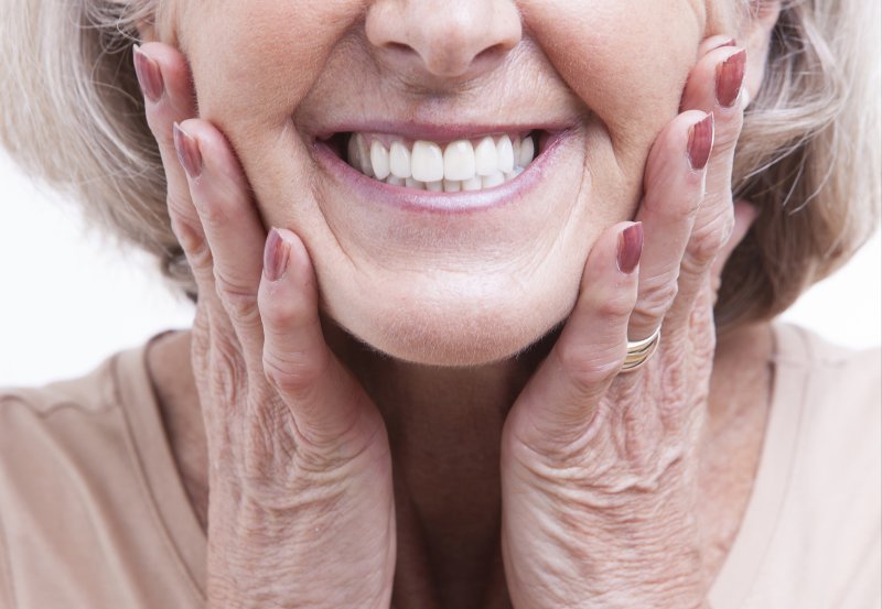 an up-close view of an older woman’s smile and her hands holding both sides of her face