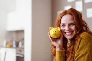 Woman holding piggy bank, used dental financing for cosmetic services