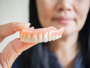 a patient smiling and holding their dentures