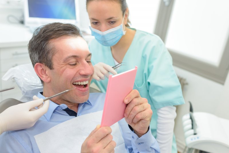 A man in a dentist's chair smiling after his dental checkup