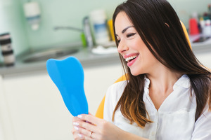 Female dental patient smiling and looking at mirror