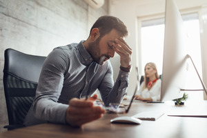 Man holding glasses while stressed out at work