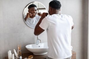 Man flossing his teeth in front of bathroom mirror 
